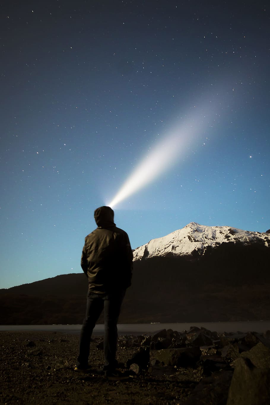 man standing in front of mountain watching light on sky, man standing in front mountain