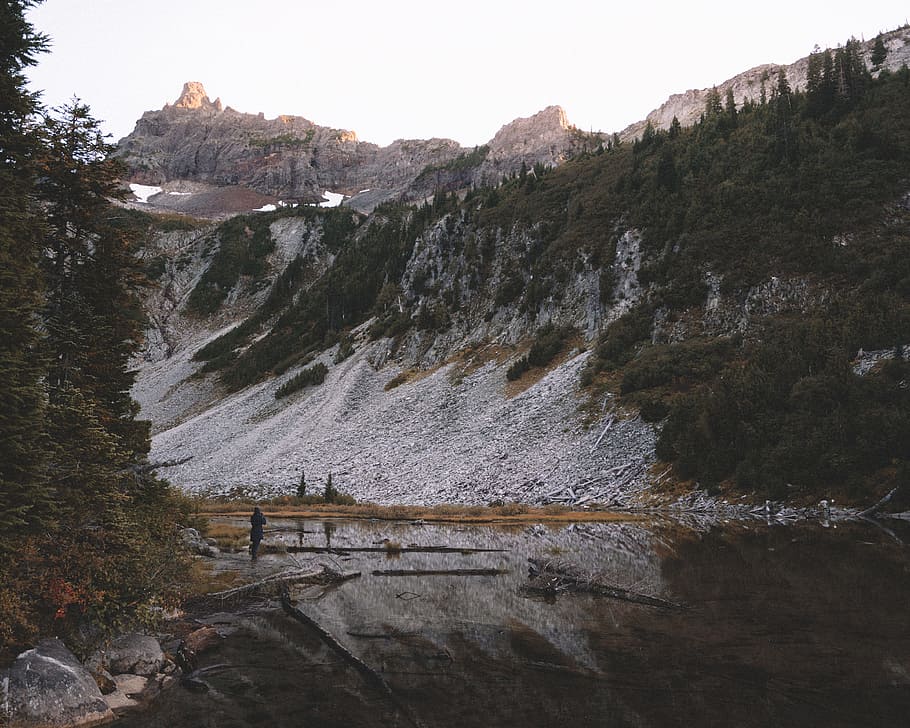 rocky mountain under white sky, lake near cliff during daytime HD wallpaper