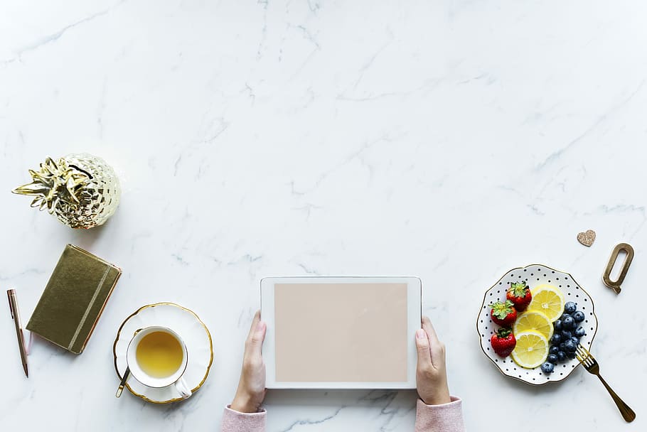 flat-lay photography of person holding tablet computer beside fruits and cup of tea HD wallpaper