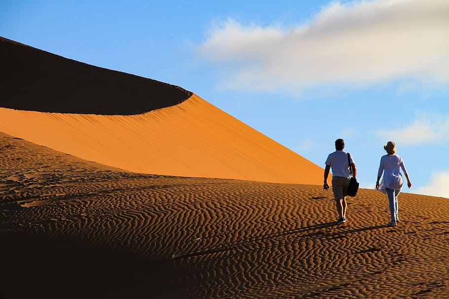 man and woman walking on desert, two person walking on desert during daytime HD wallpaper