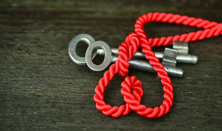 two silver keys and red rope on gray wooden surface, heart, love