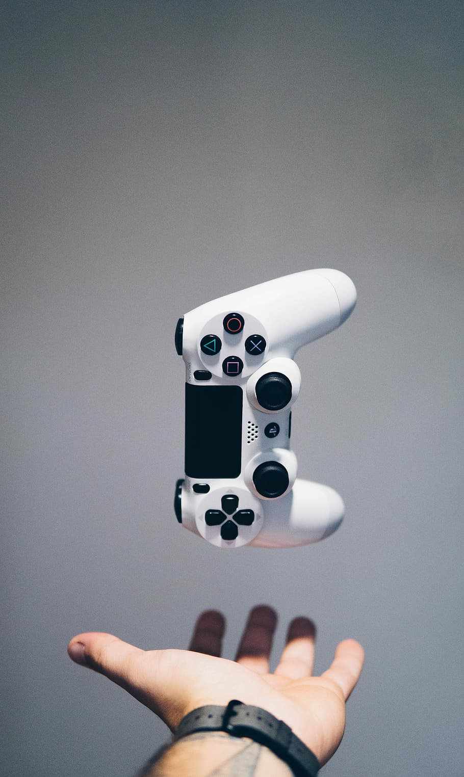 white Sony PS4 DualShock controller over person's palm, white Sony PS4 Dualshock 4 wireless controller