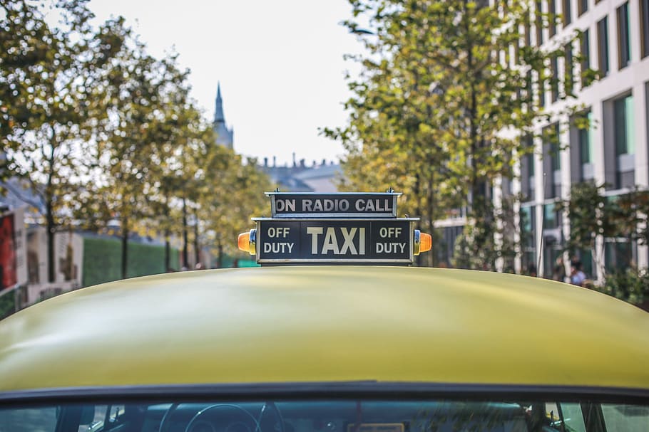 selective focus photography of taxi cab signage, yellow Taxi vehicle during daytime