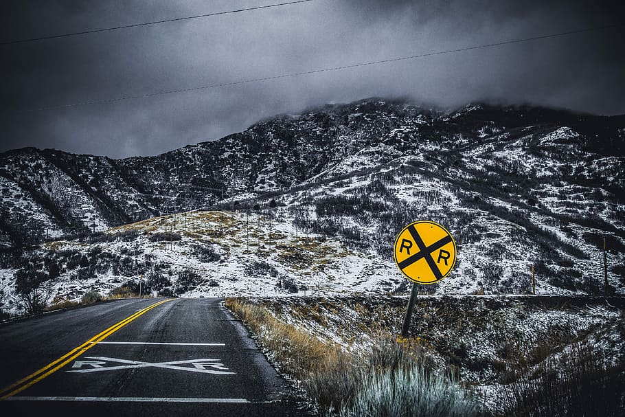 yellow and black road signage on roadside, yellow and black road sign beside gray concrete road with view of snow-capped mountain photo, HD wallpaper