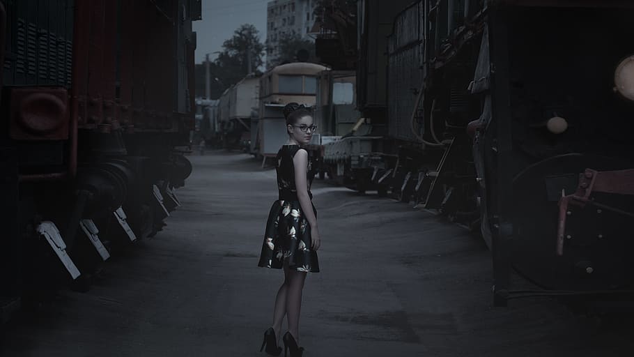 vignet photography woman in black dress standing between trains