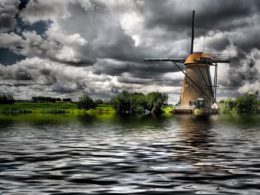 brown windmill near body of water under gray clouds during daytime HD wallpaper