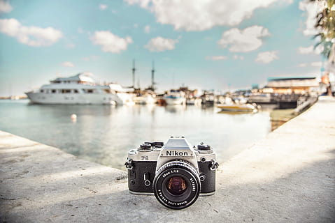black and silver Nikon camera near boats during daytime, gray and black Nikon SLR camera on edge of gutter HD wallpaper
