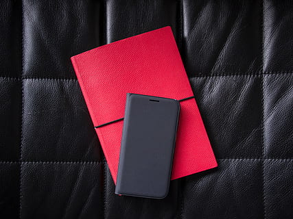 black smartphone flip case on top of red file folder, leather HD wallpaper