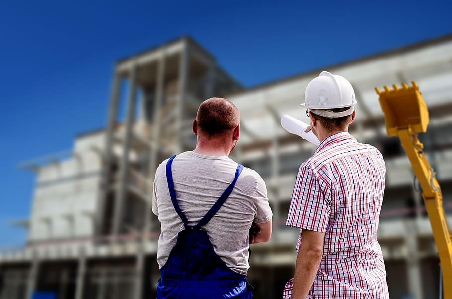 two men standing in front of concrete structure during daytime