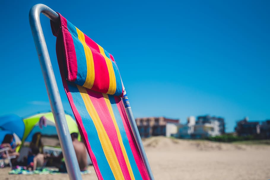 selective focus photography of lounge chair, red, blue, and yellow stripe lounger