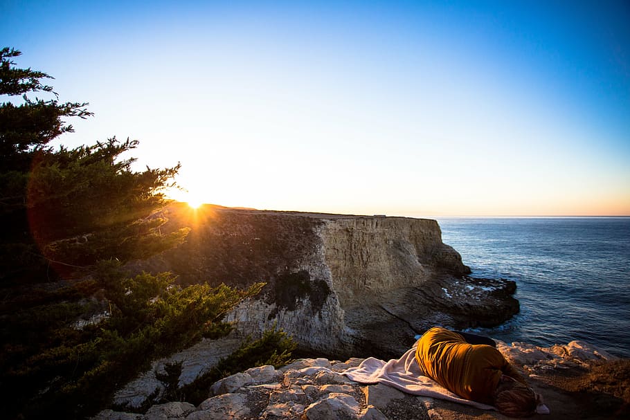 coast, person, sleeping, lying, blanket, cliff, rock, shore HD wallpaper