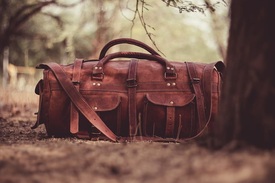 selective focus photography brown leather 2-way handbag near tree, brown leather satchel duffel bag beside brown tree during daytime, HD wallpaper