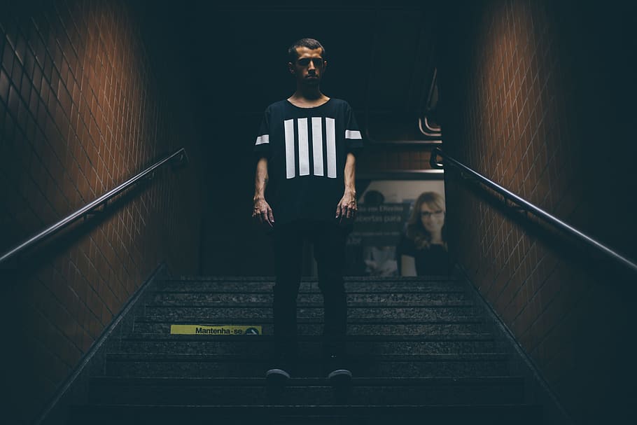 man wearing black and white shirt standing in the middle of stairs, HD wallpaper
