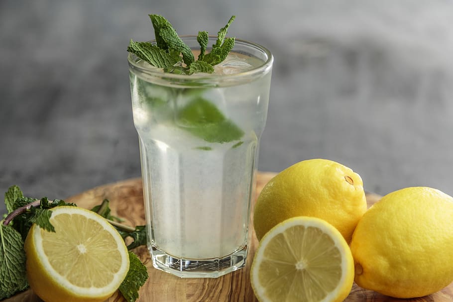 lime juice on drinking glass beside sliced limes, clear drinking glass with sliced lemonades