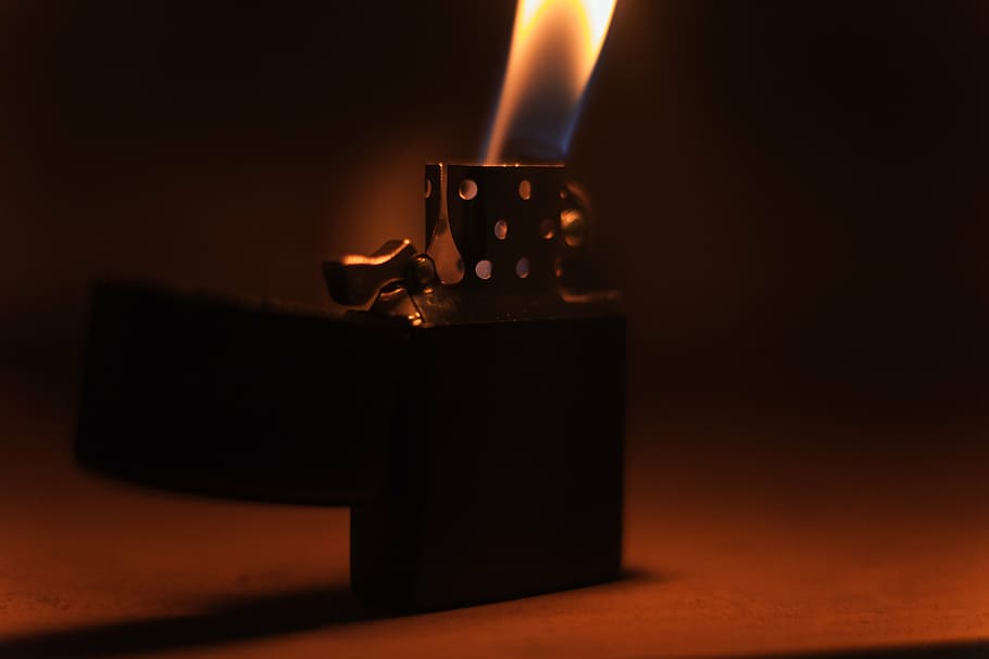 close-up photo of lighted lighter on brown surface, black, flip
