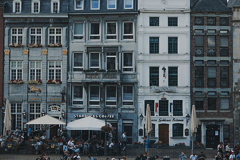white patio umbrellas in front of buildings, people near building during daytime HD wallpaper