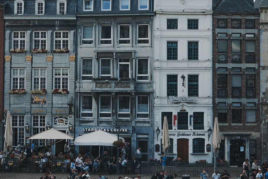 white patio umbrellas in front of buildings, people near building during daytime HD wallpaper