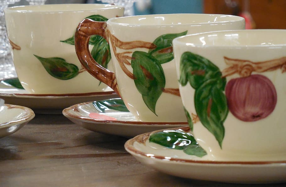 three white-green-and-red fruit themed ceramic teacups, drink