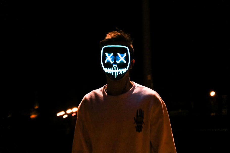 man standing in the dark wearing lighted stitched mouth and crossed eyes mask, portrait, light, man, hoodie, mask
