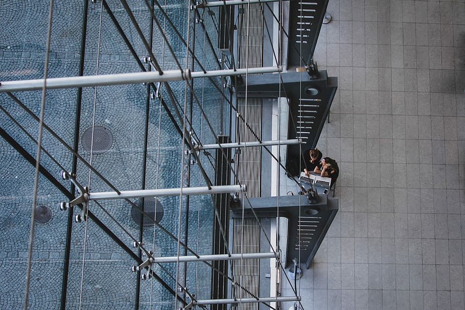 aerial photography of man and woman sitting near gray metal pillars, untitled HD wallpaper