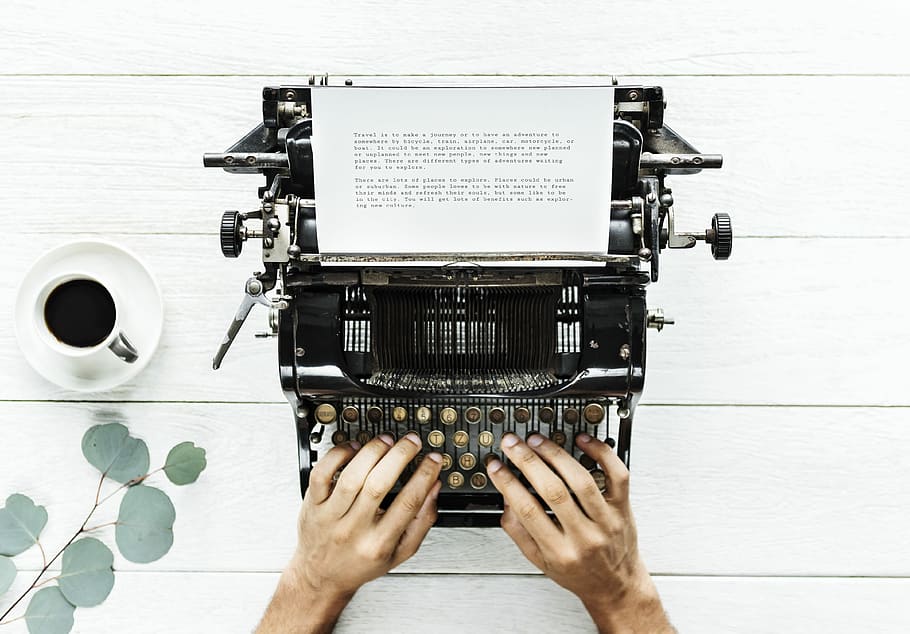 person place hands on black typewriter beside white cup filled with black liquid on saucer HD wallpaper