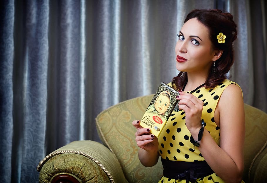 woman in yellow and black polka-dot sleeveless top sitting on sofa chair, HD wallpaper