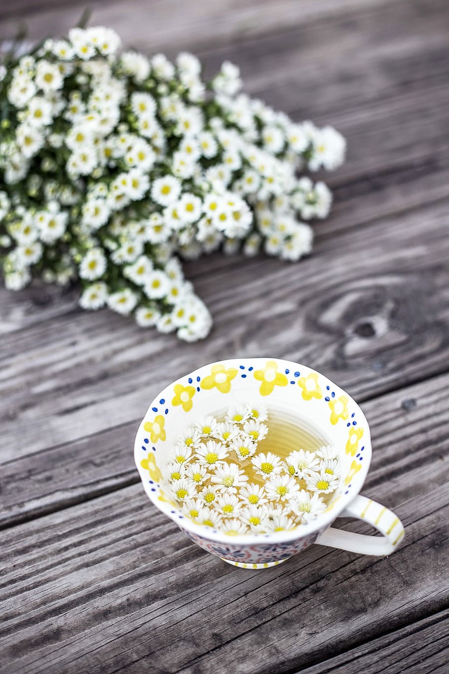 white and yellow cup with flowers on table, floral ceramic teacup with white flowers on wooden table, HD wallpaper