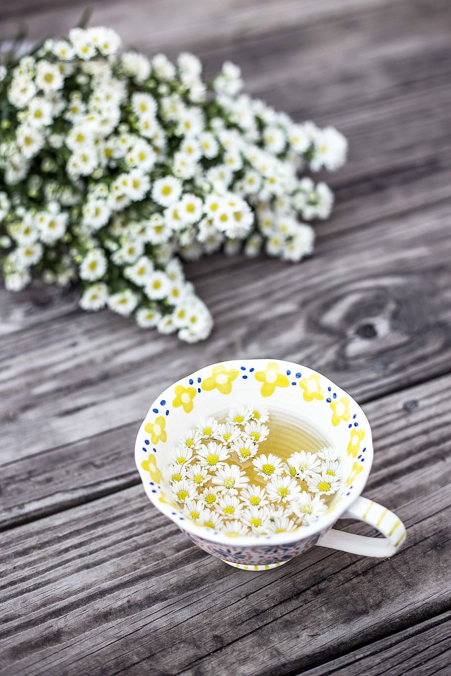 white and yellow cup with flowers on table, floral ceramic teacup with white flowers on wooden table HD wallpaper