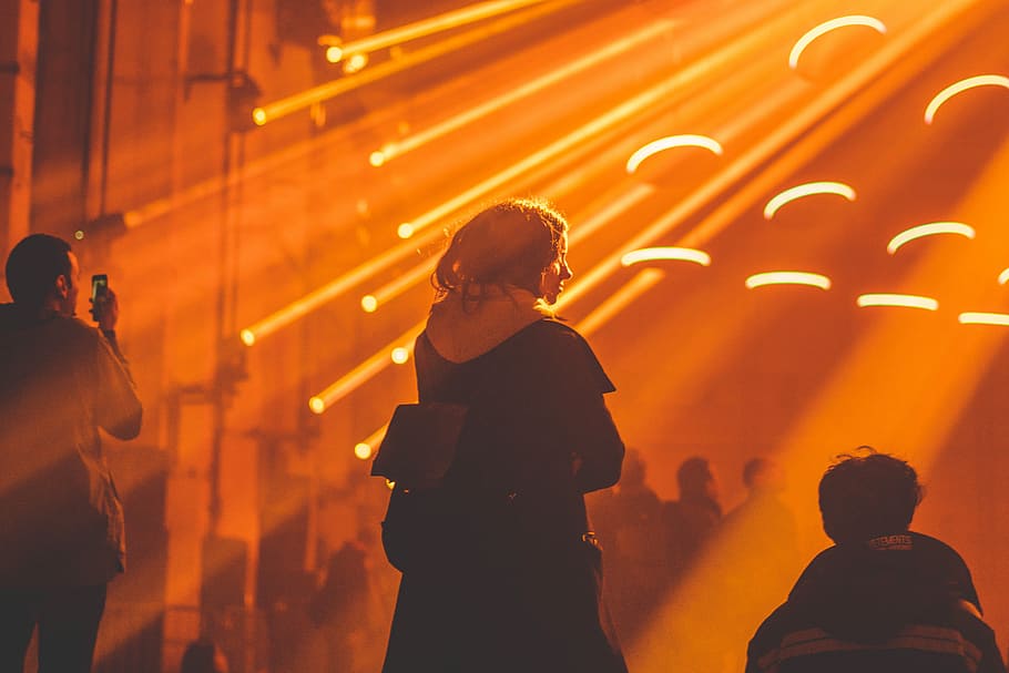 person standing being shined by light, woman near rays of orange lights HD wallpaper