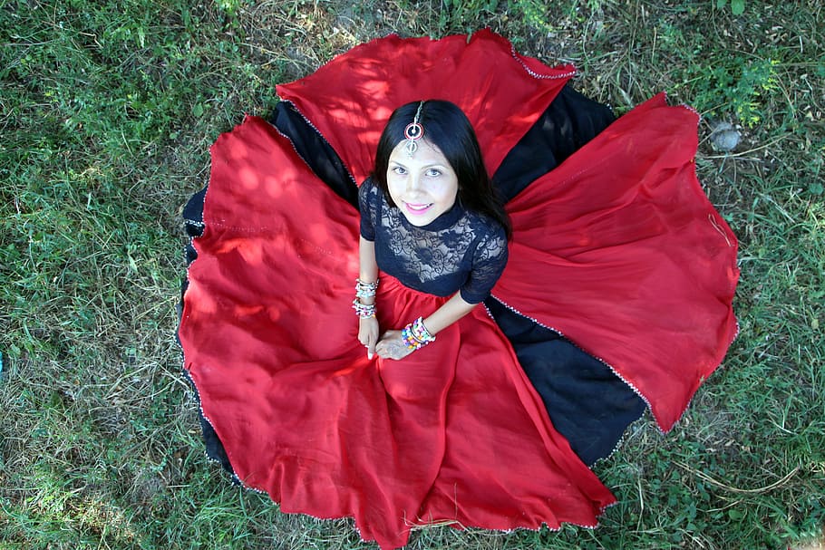 woman wearing red and black long dress sitting on the green grass looking up, HD wallpaper