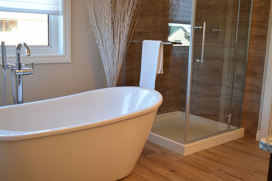 white ceramic bathtub beside a clear glass shower enclosure and an open window