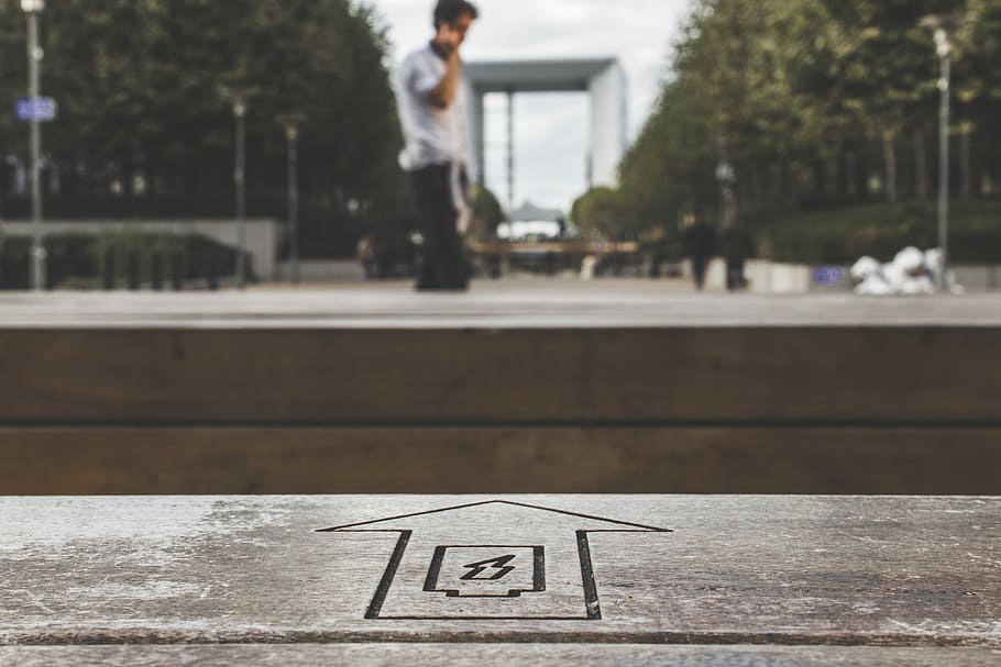 arrow sign heading to man using smartphone during daytime, selective focus photography of arrow up pointing at man holding phone