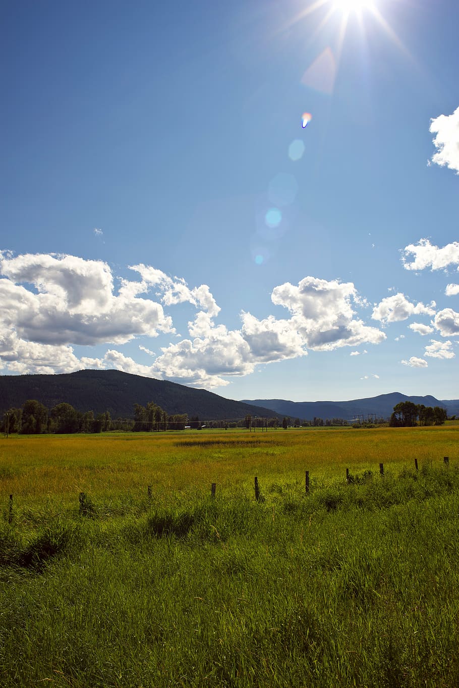 mountain, sun, flare, clouds, field, fence, sky, landscape HD wallpaper