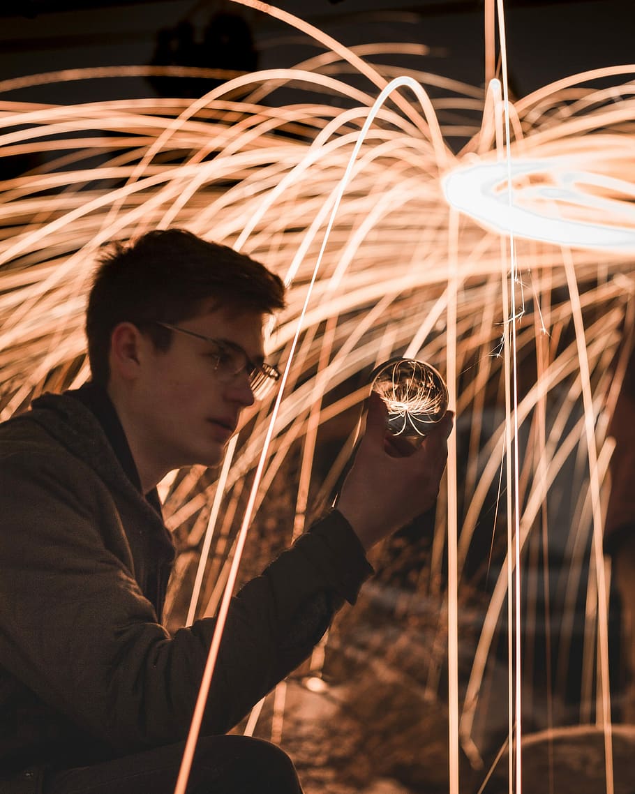 man holding crystal ball, man wearing black jacket, firework HD wallpaper