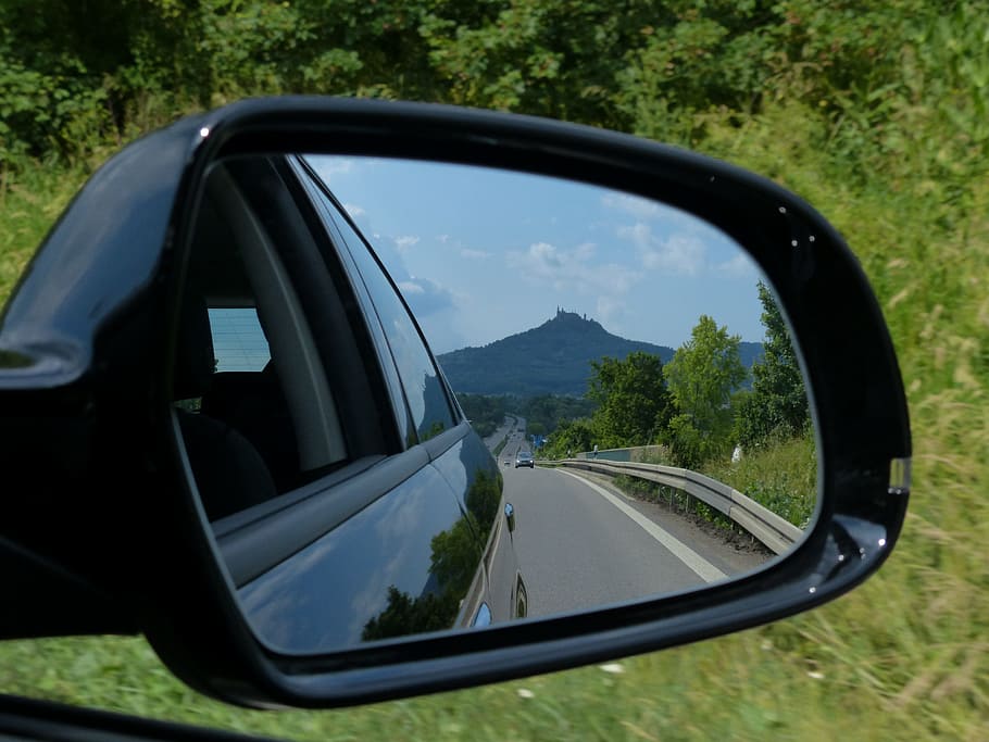 black vehicle side mirror with reflection of trees, rear mirror