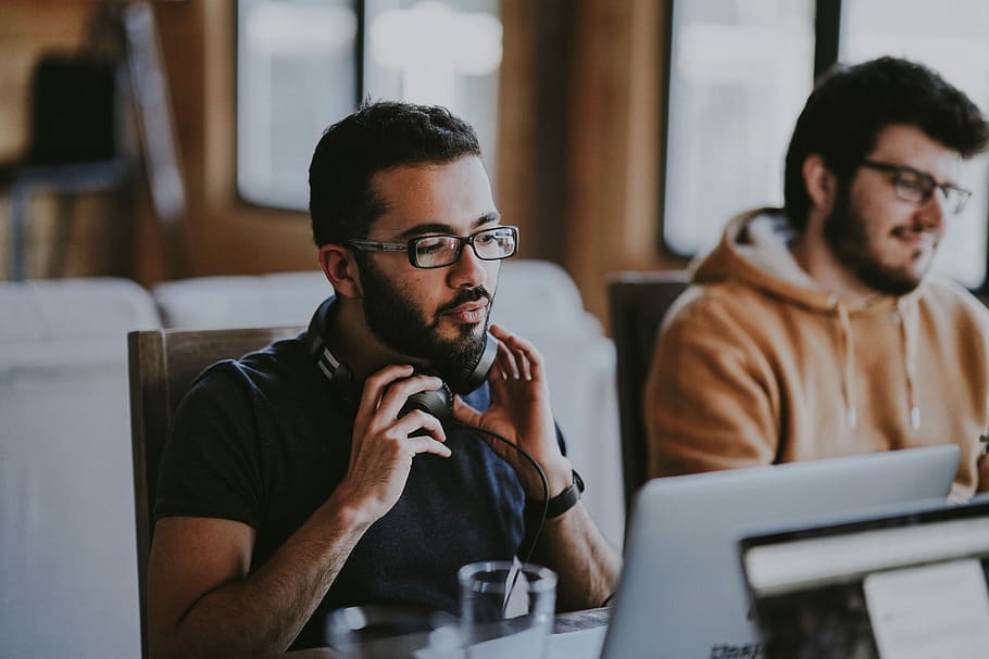 man wearing eyeglasses and headphones beside smiling man, man holding his headset HD wallpaper