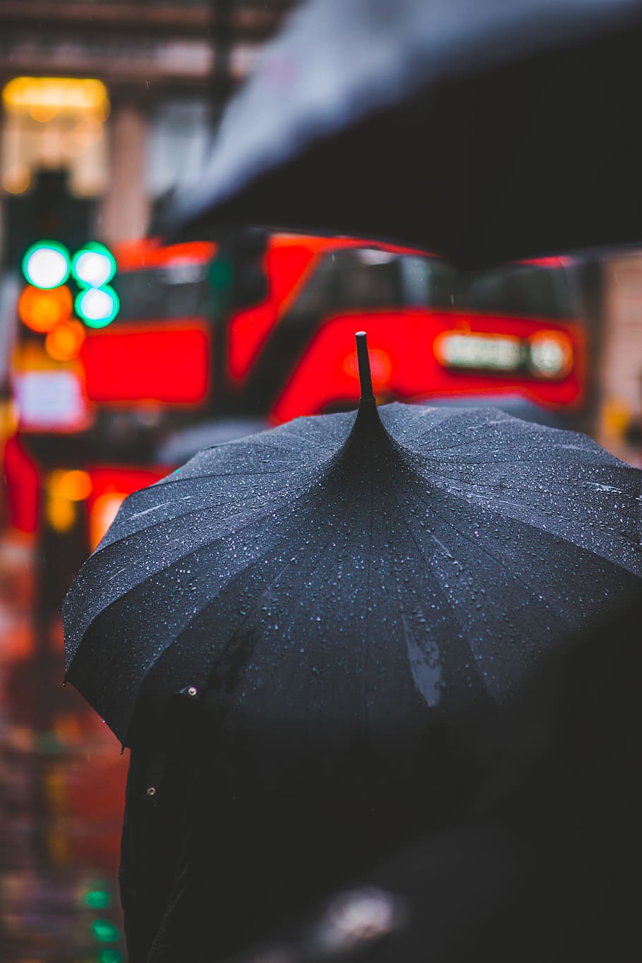 person holding black umbrella, person holding using black umbrella while raining walking outside during daytime