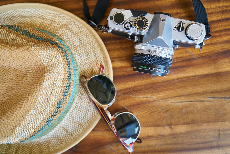 black and gray DSLR camera beside a sunglasses and hat on table HD wallpaper
