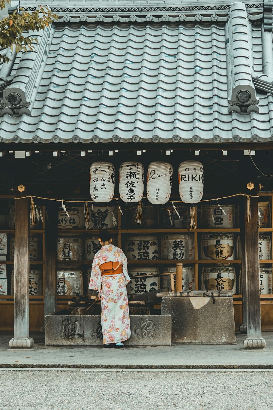 woman wearing orange and white kimono dress standing near the house, woman standing in front of house