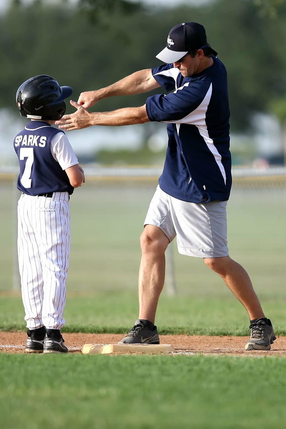 man teaching boy how to swing a bat on base during daytime, baseball