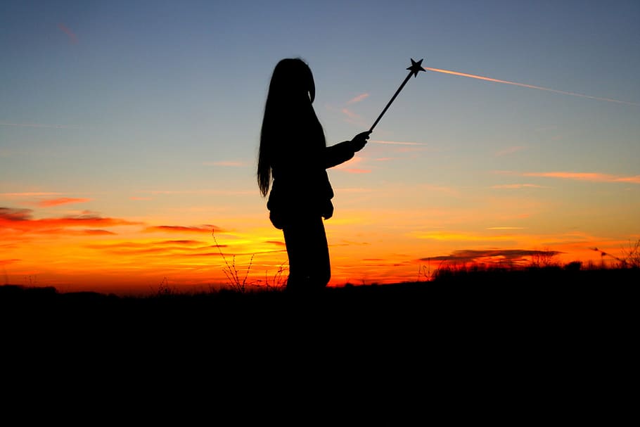 silhouette of woman holding star stick during dawn, sunset, girl