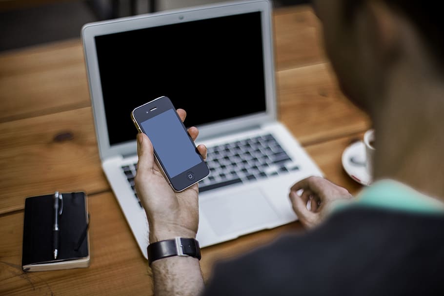 person holding turned off iPhone in front of turned off MacBook Air, HD wallpaper