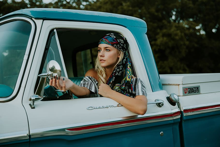 woman in white and grey shirt sitting inside pickup truck while looking mirror during daytime HD wallpaper