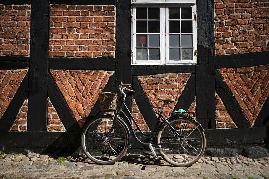 black cruiser bike near brown painted house, black beach cruiser bike near brown brick wall