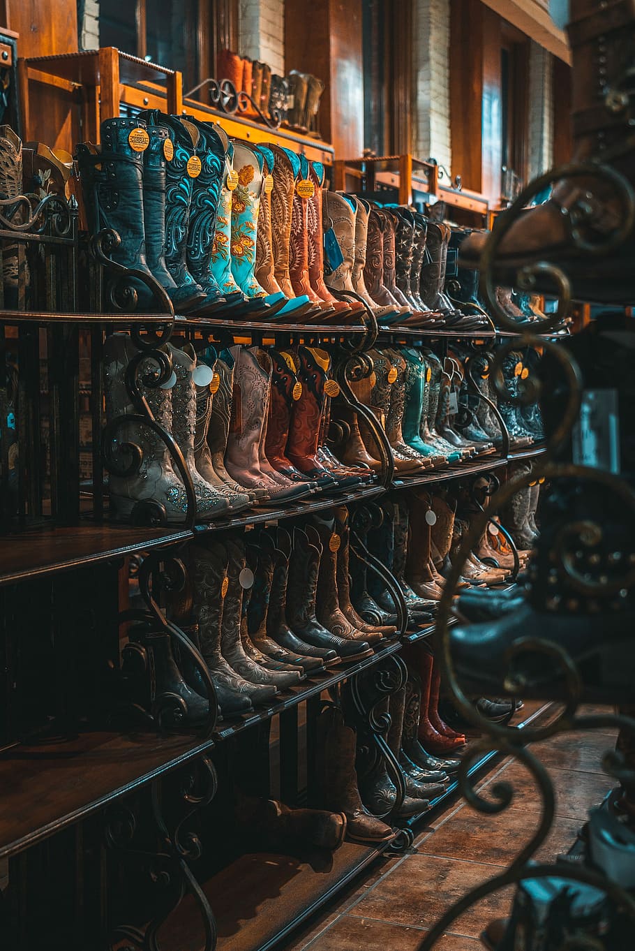 brown and blue leather cowboy boots on rack, photo of cowboy boots collection