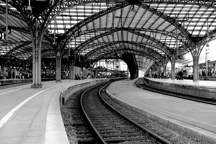 grayscale photo of trainstation interior, cologne main station