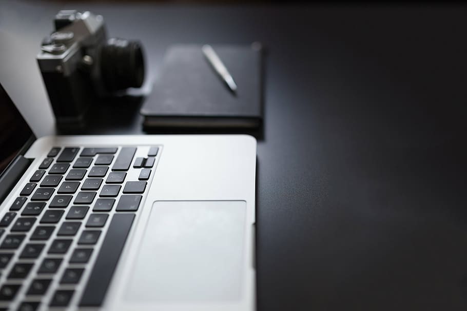 MacBook Pro beside camera, notebook and pen, black, grey, laptop