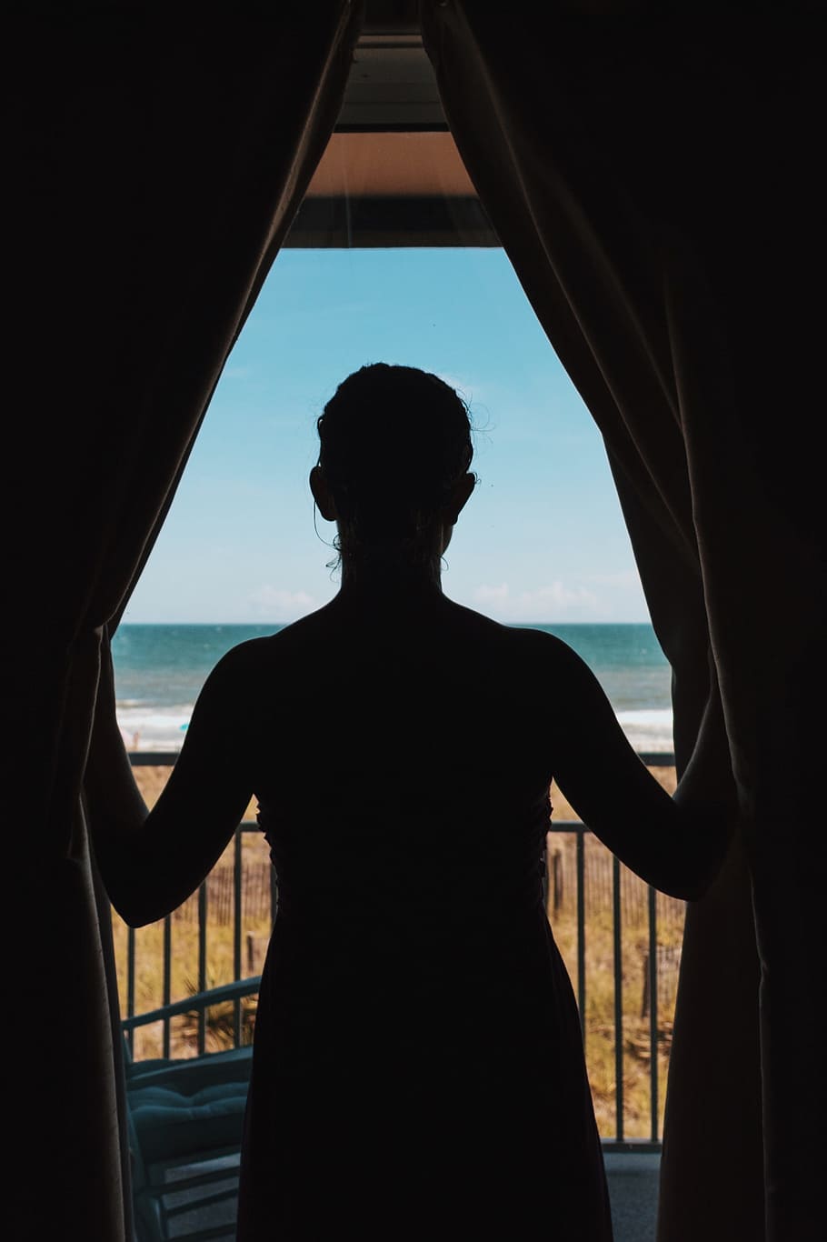 silhouette photo of woman standing between curtains, silhouette photo of woman near the window