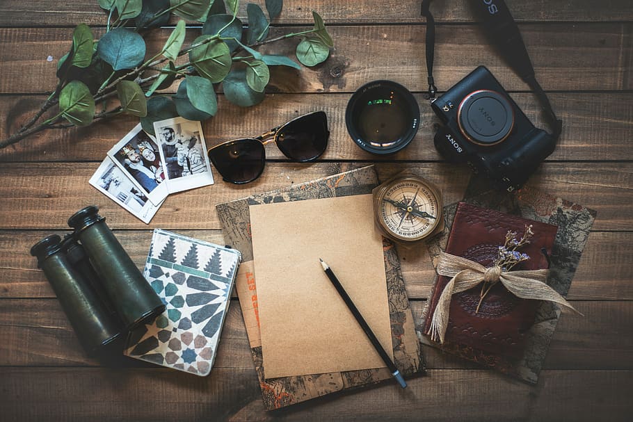 photo of assorted items on wooden table, sunglasses, camera, binocular with pen and cards on brown wooden surface HD wallpaper