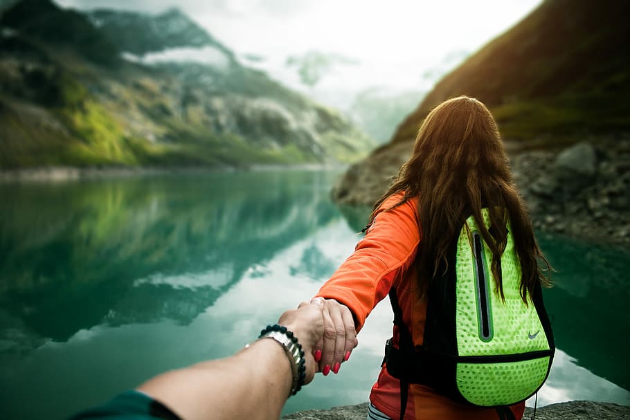 woman holding man's hand in front of water, woman near body of water taken at daytime HD wallpaper